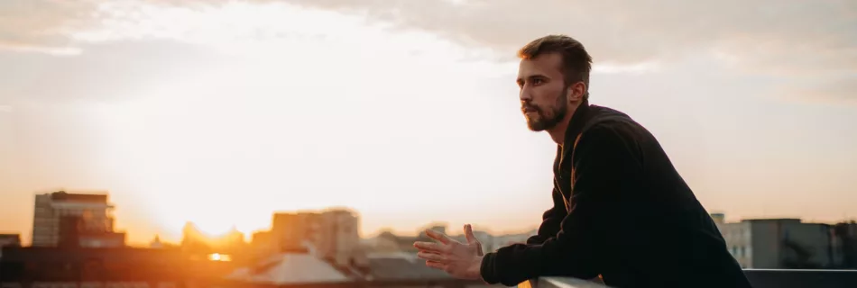 Man ponders how he will integrate what he found on his journey while on a rooftop